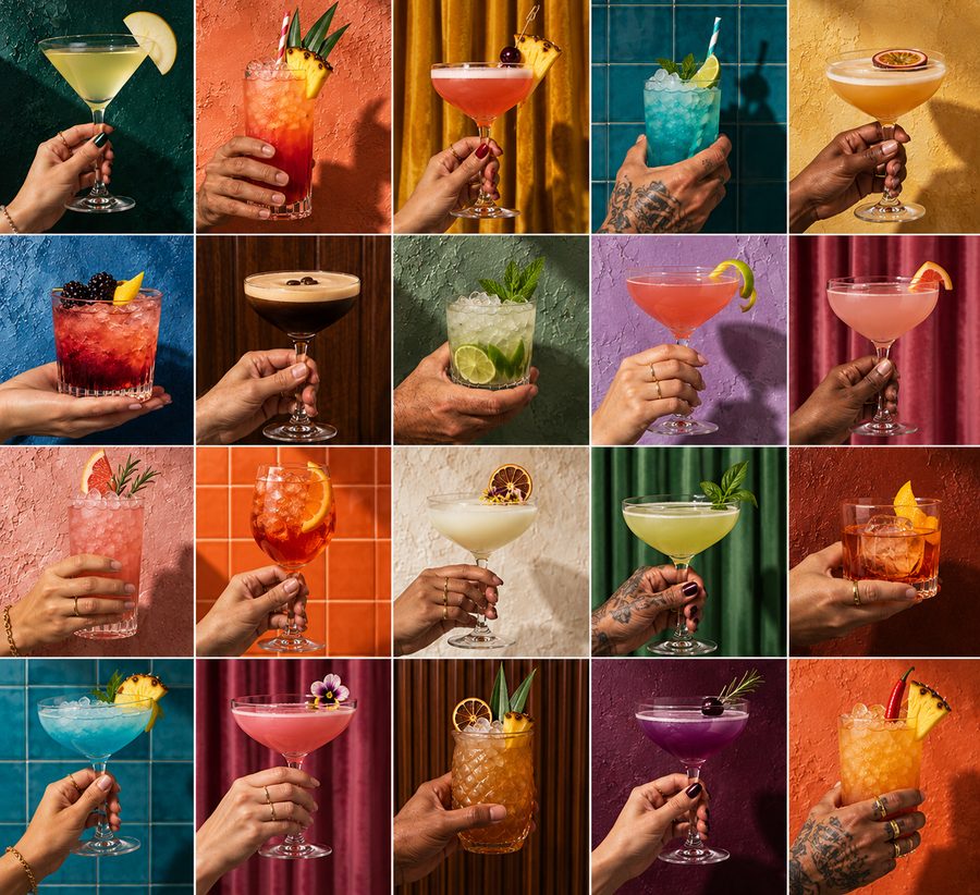 A grid of twenty colourful cocktails held up in hands against painted walls