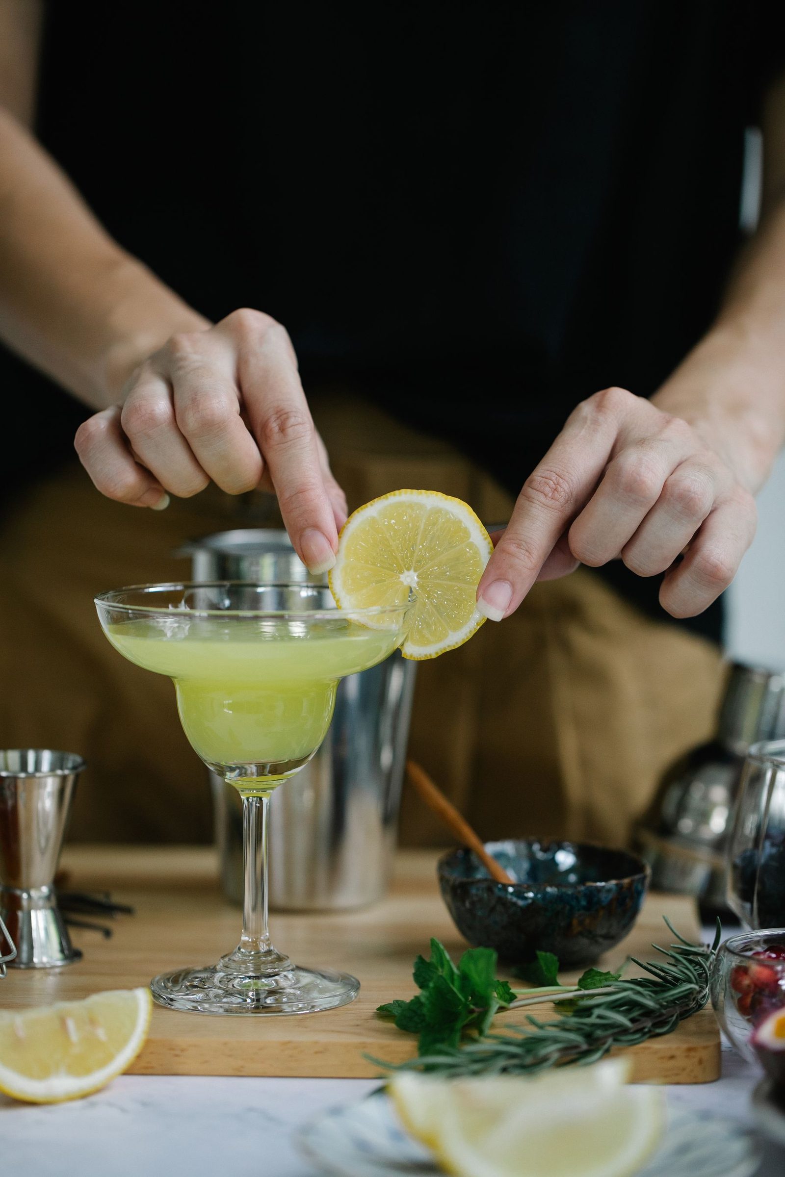 Hands garnishing a margarita with a slice of lemon