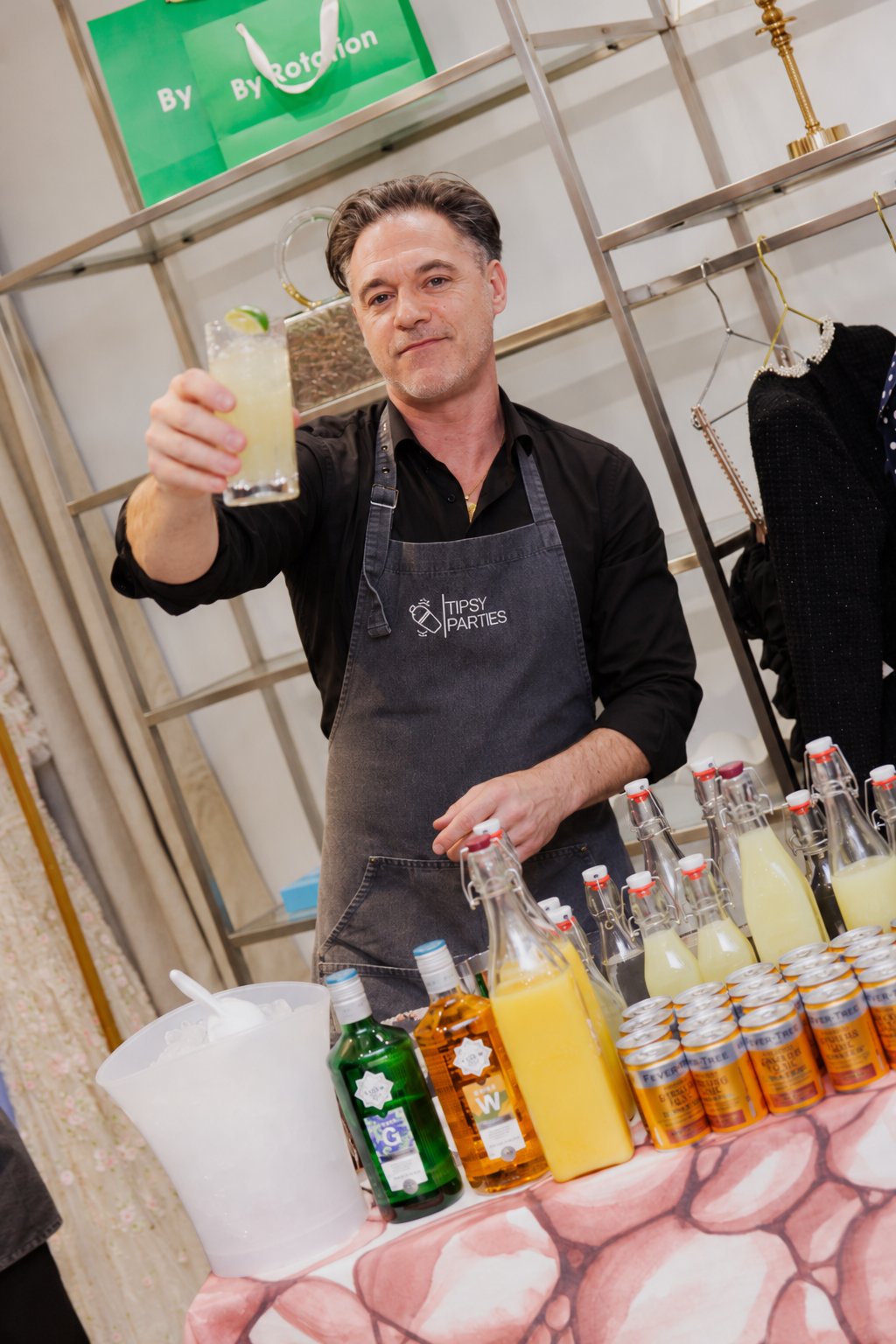 The Tipsy Parties mixologist smiling and holding up a finished cocktail with a lime wedge