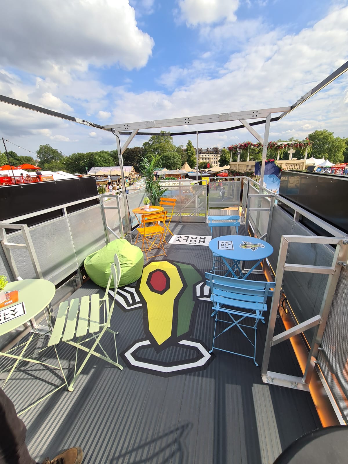 The Holy Moly rooftop deck with bright café tables, a beanbag and a giant avocado painted on the floor, overlooking the festival