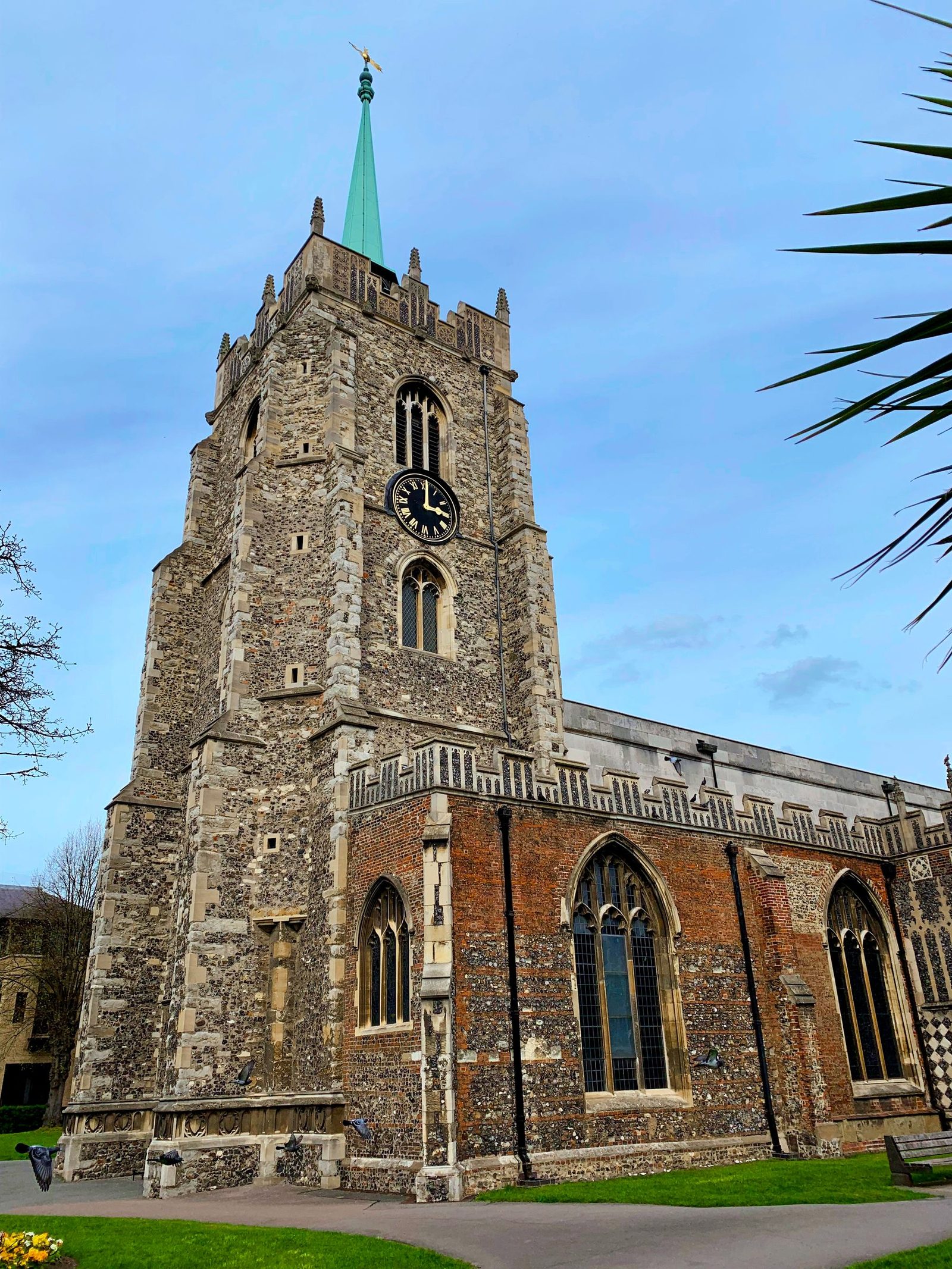 A flint and stone church tower in Chelmsford against a blue sky