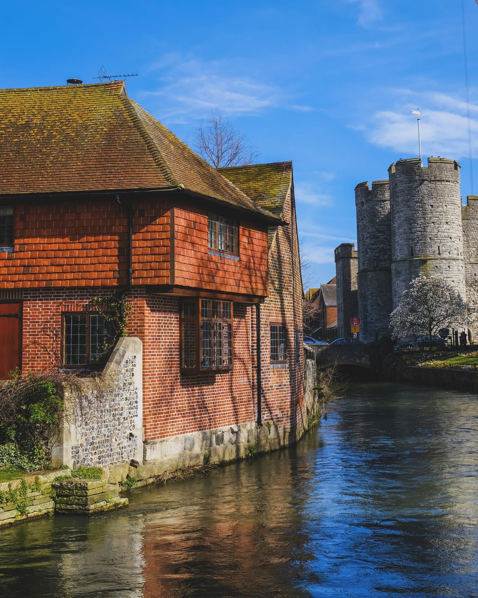 The Westgate Towers beside a river and a red brick house in Canterbury, Kent
