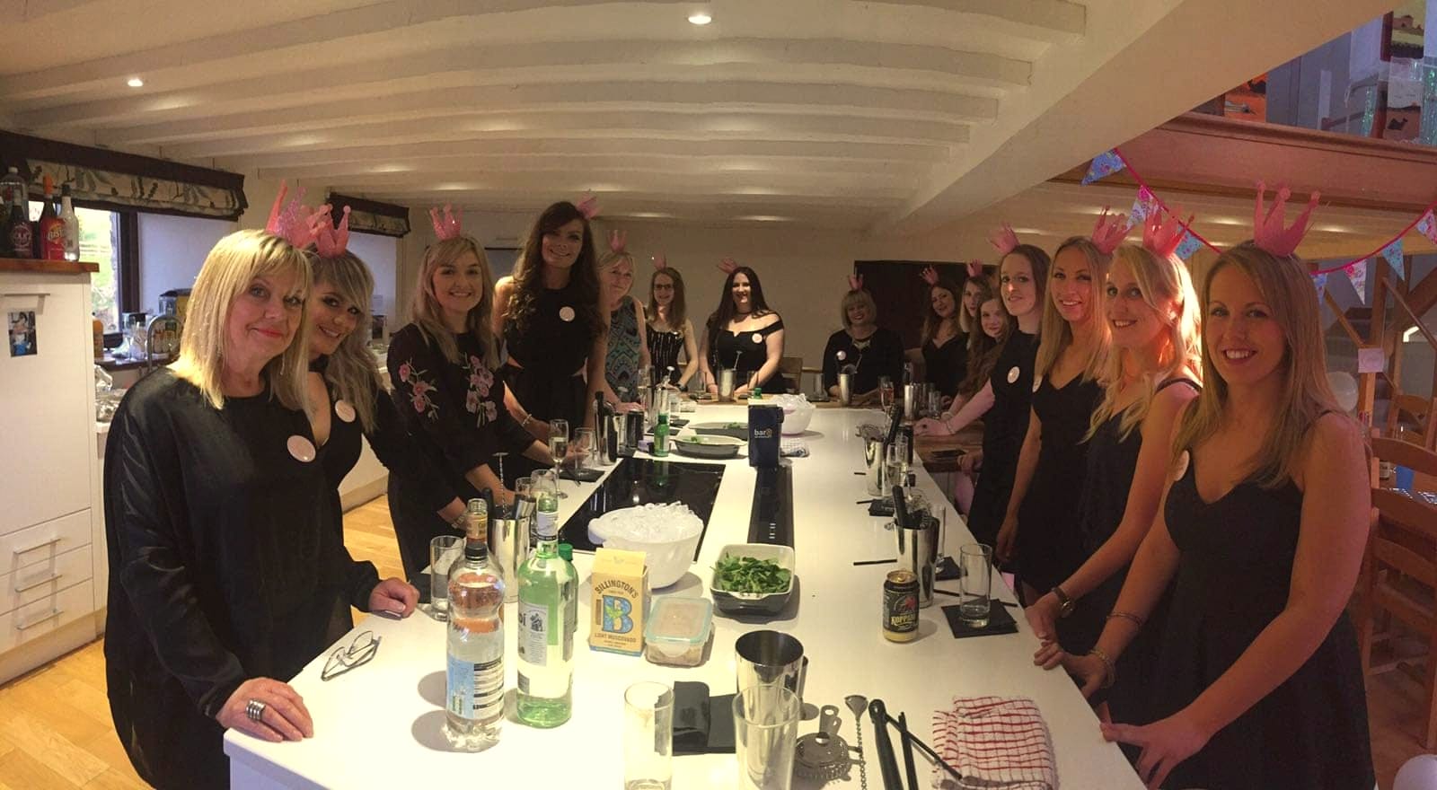Group in party ears standing round a long kitchen island with their cocktails