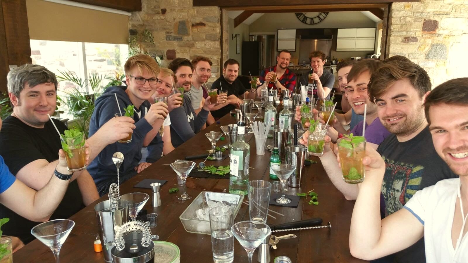 Group at a long table raising martini glasses in a farmhouse kitchen