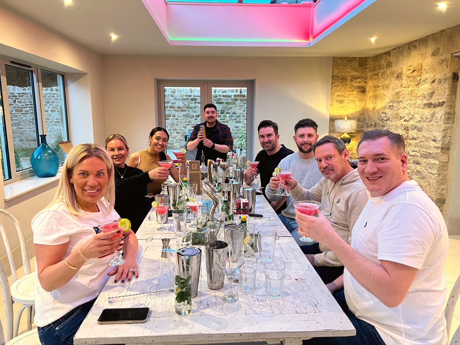 Mixed group at a long table raising pink cocktails at a class