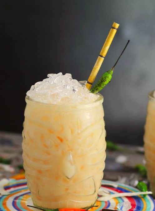 Creamy cocktail with crushed ice, a bamboo straw and a green chilli in a tiki glass