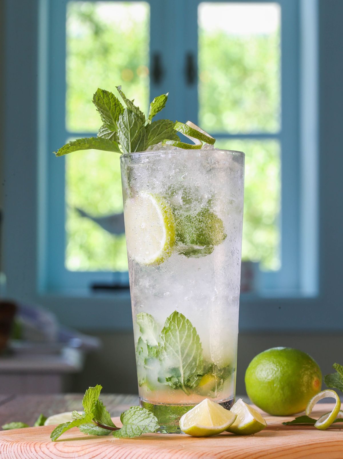 A tall mojito with mint and lime by a bright window