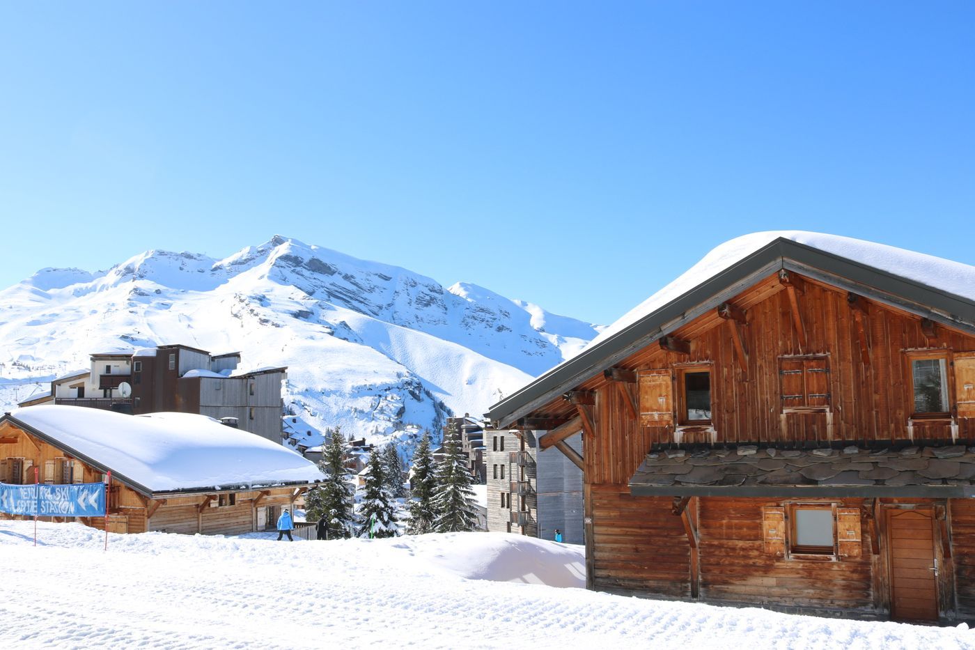 Scenic view of snowy alpine village with rustic wooden cabins in the mountains