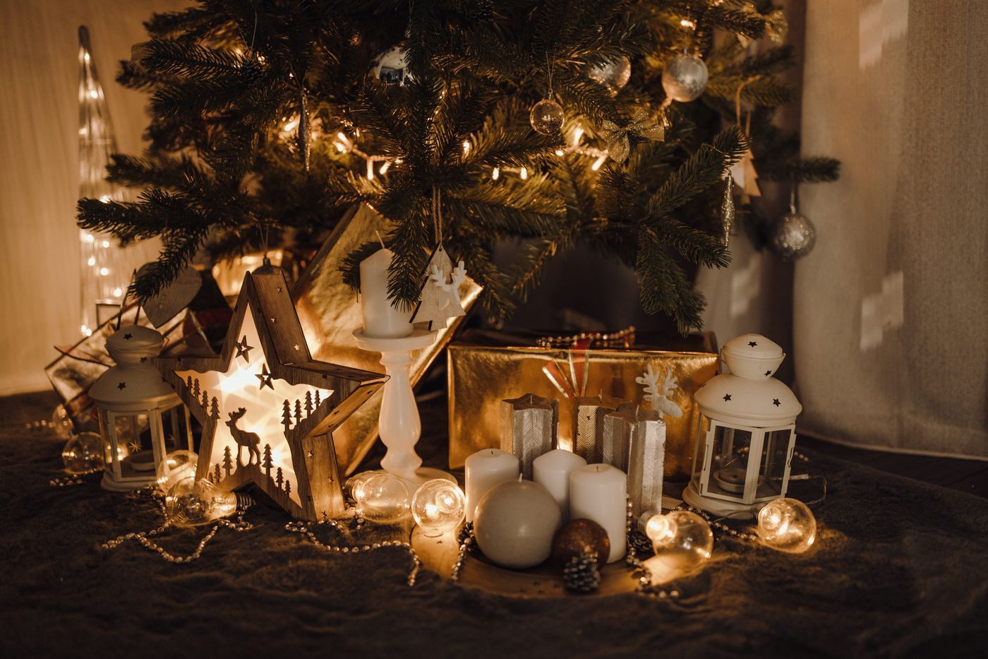 A warm and festive Christmas scene with ornaments and candles under a tree