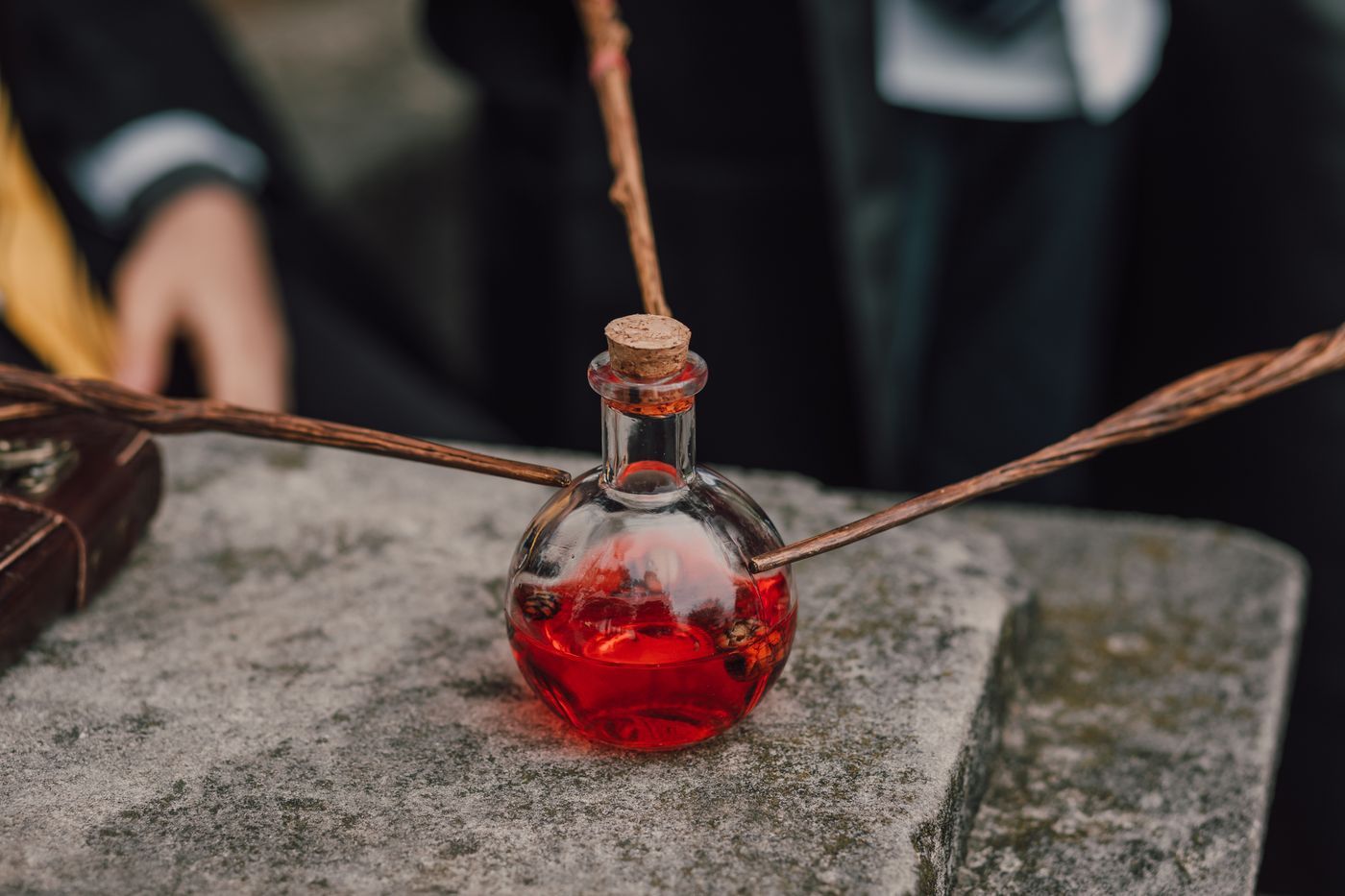 Mysterious red potion in a glass bottle with magic wands, invoking an enchanting alchemical atmosphere