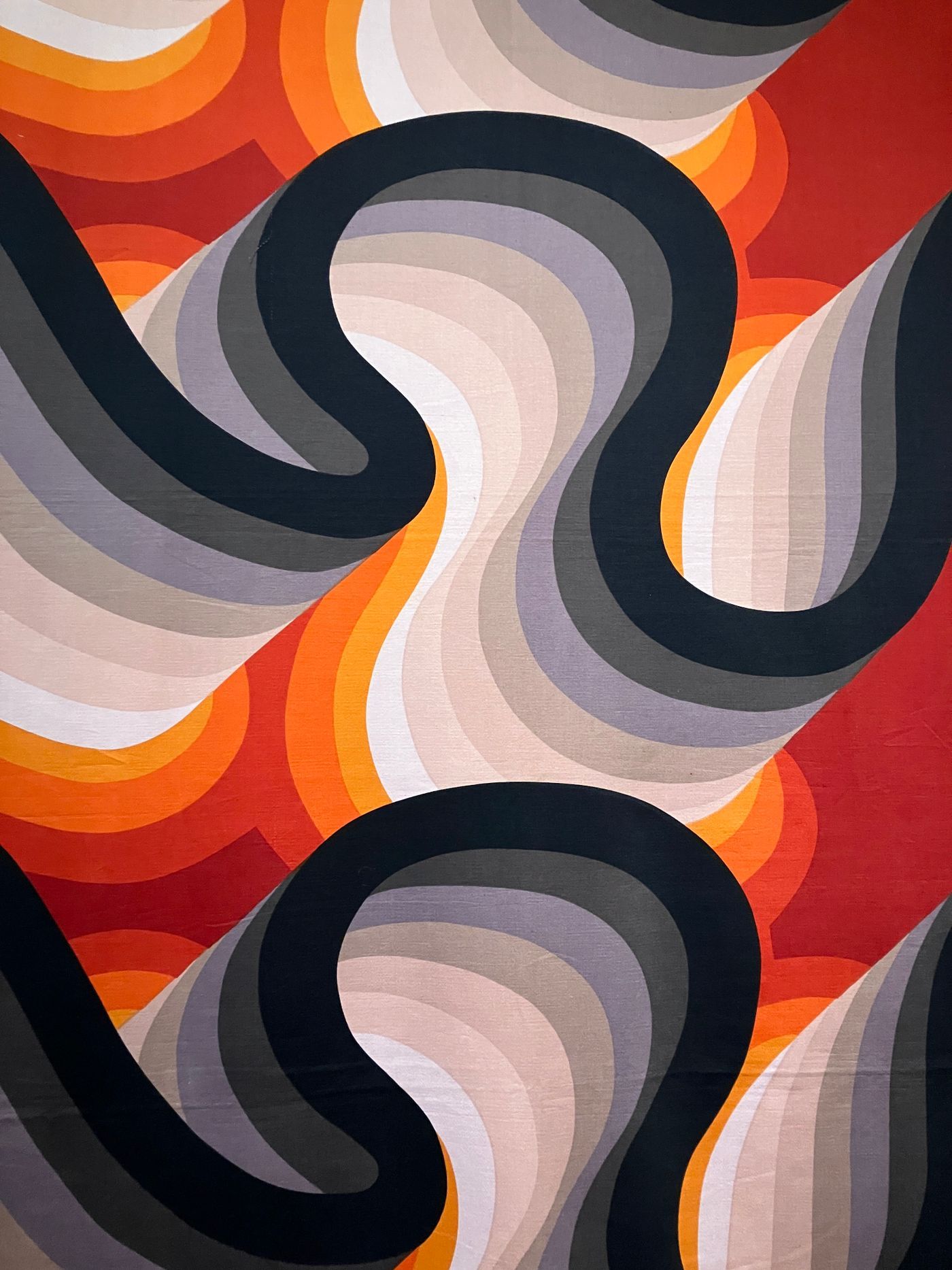 Colorful abstract textile with bold curves and vivid orange, red, and violet hues