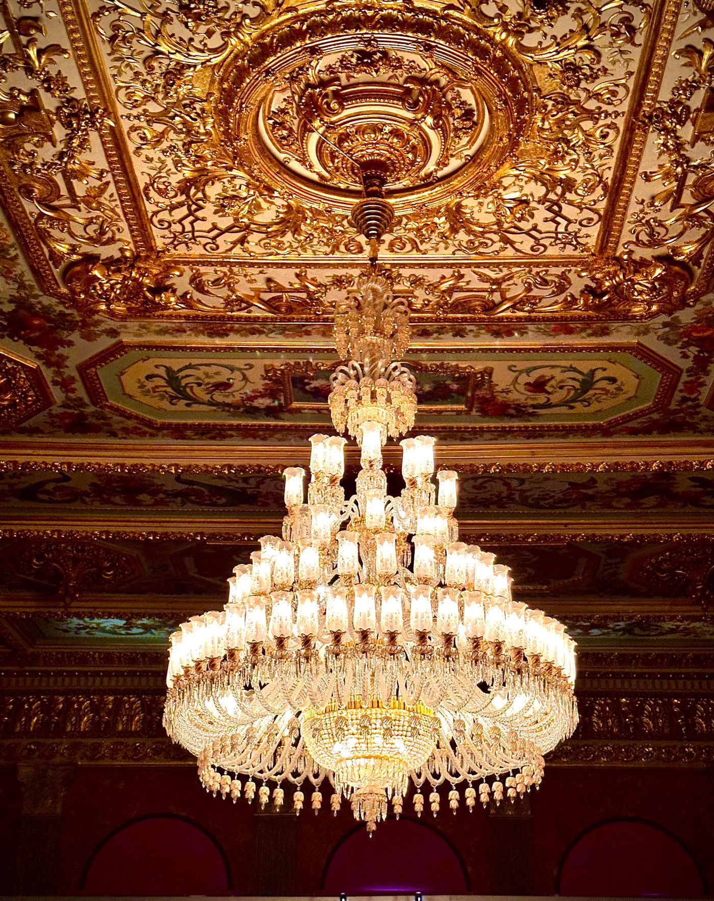 Stunning crystal chandelier hanging from an ornately decorated ceiling
