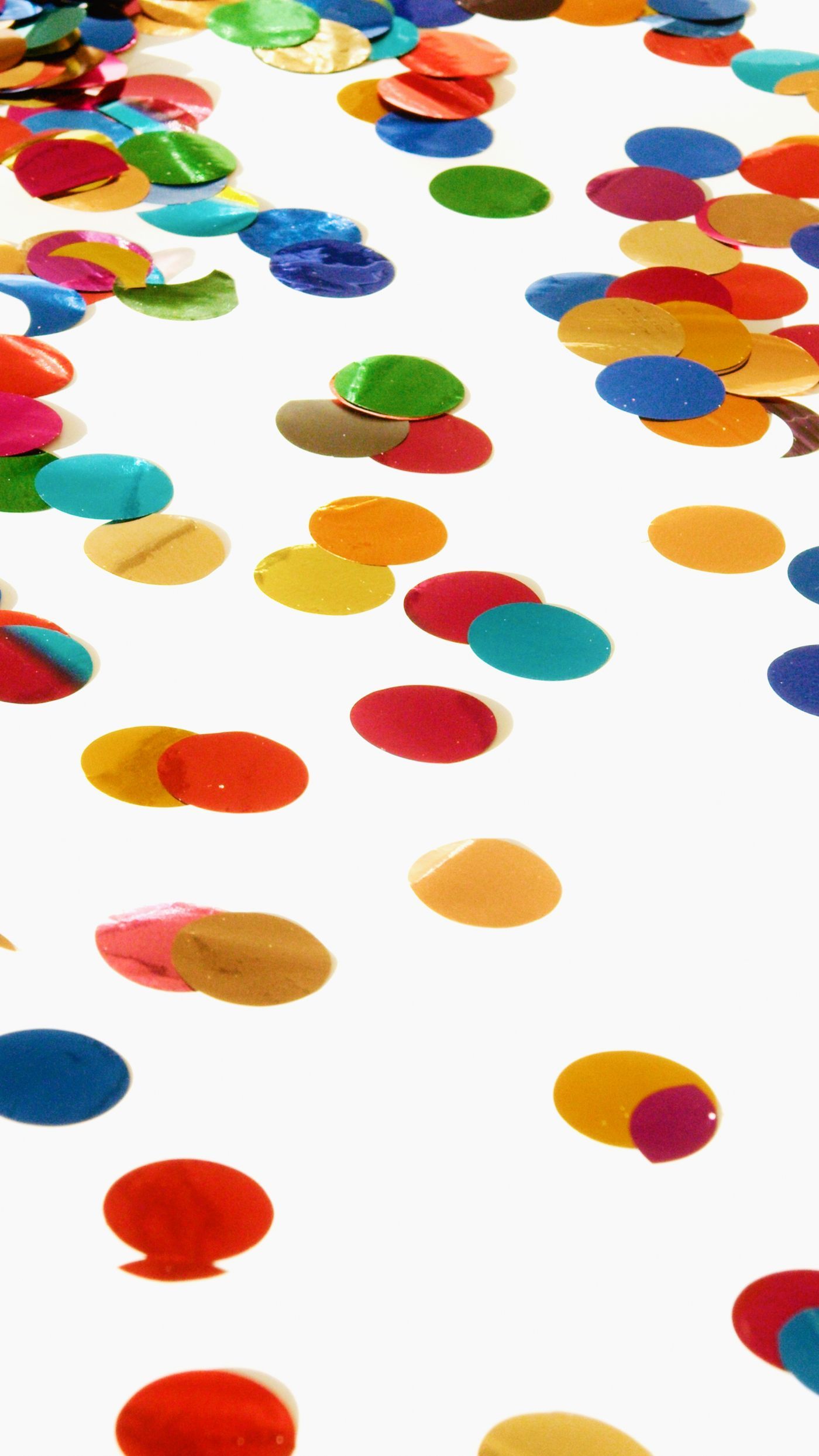 Vibrant multicolored confetti scattered on a bright white surface, creating a festive and joyful atmosphere