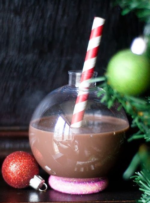 A chocolate cocktail served in a festive bauble with a stripey red and white straw